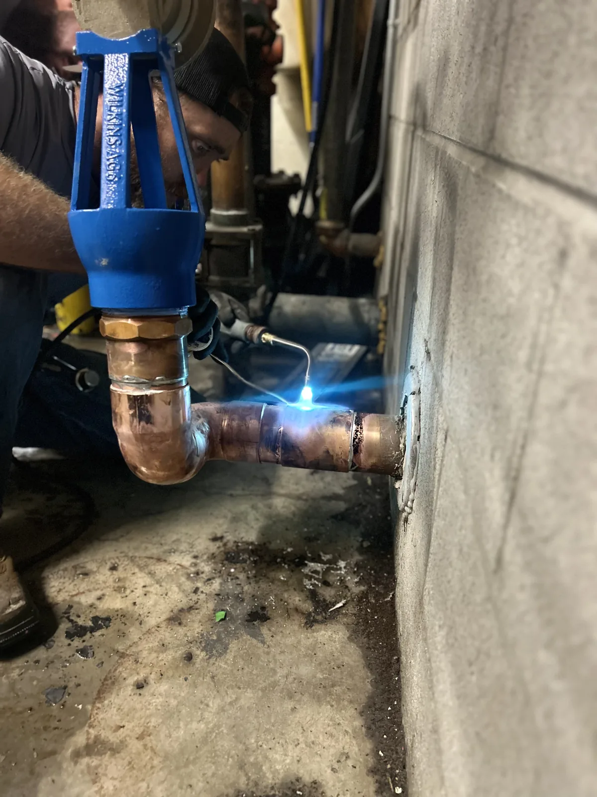 Technician soldering copper piping during a new construction backflow installation