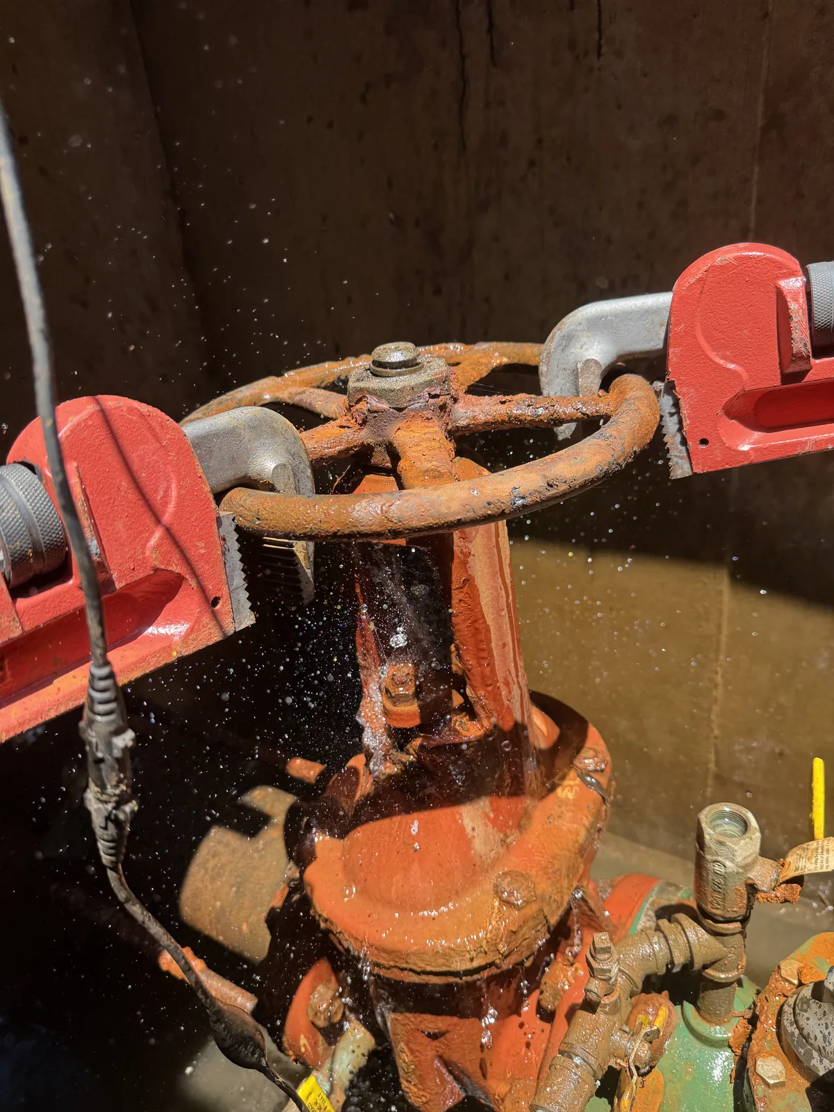 Heavily rusted fireline valve being repaired with pipe wrenches