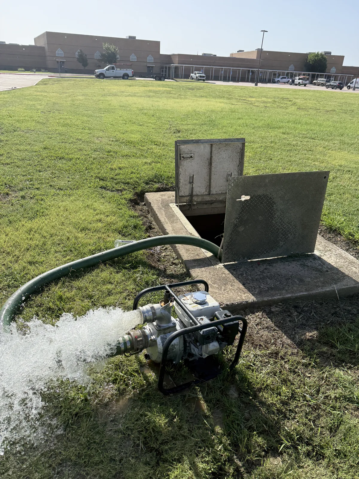 Pump removing water from a flooded underground fireline vault at a North Texas school