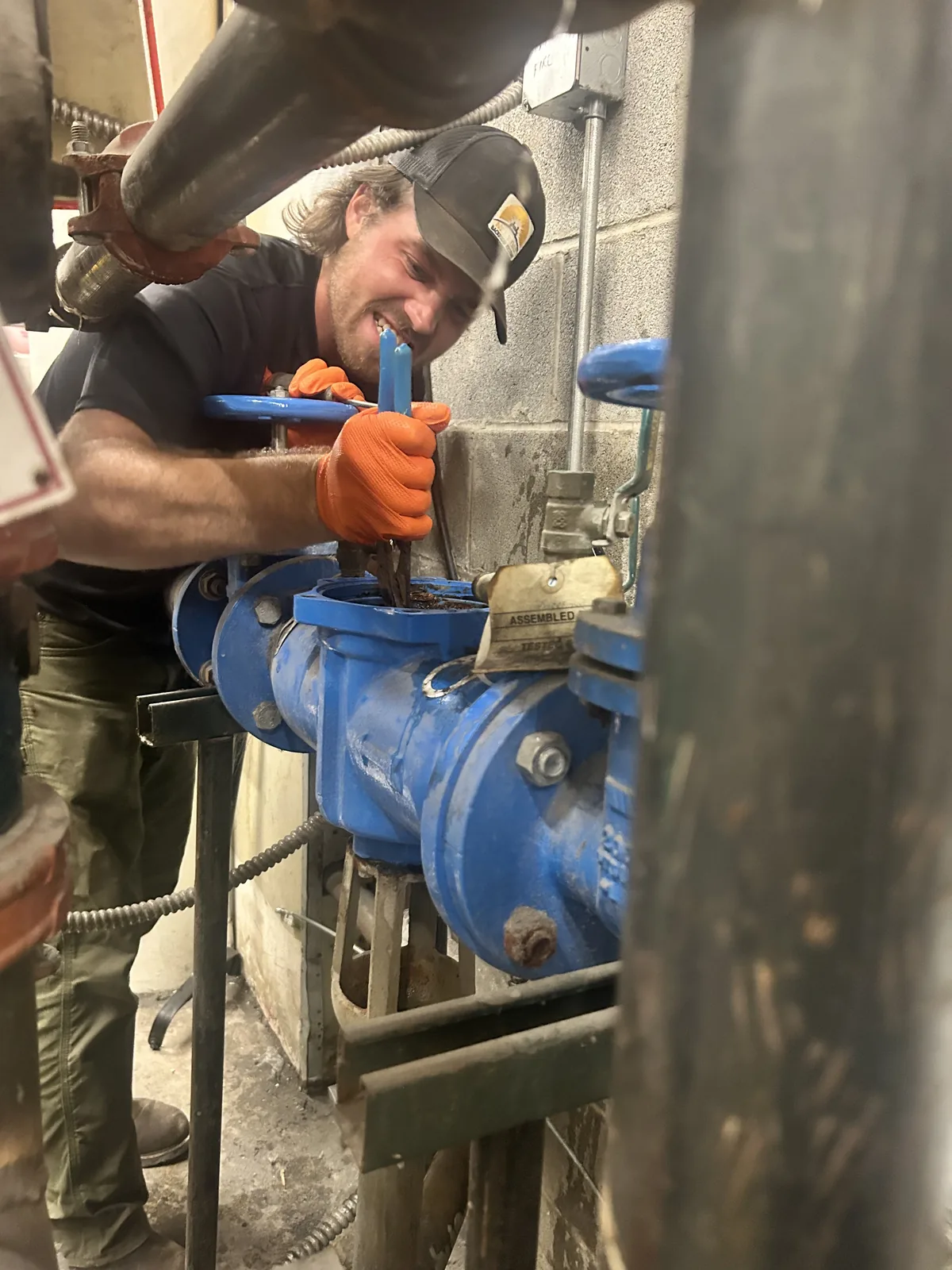 Next Day Backflow Testing technician rebuilding a large blue backflow assembly in a mechanical room
