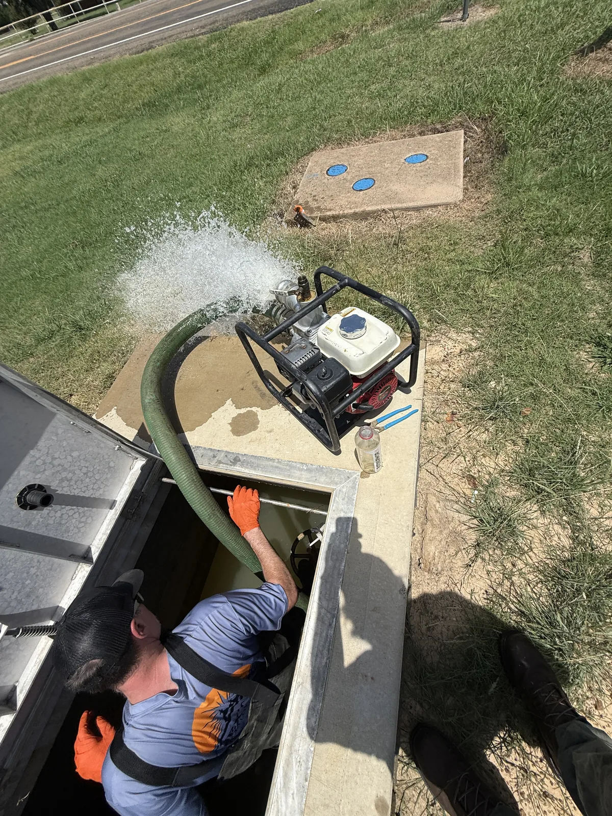 Next Day Backflow Testing technician working inside an underground vault while water is pumped out
